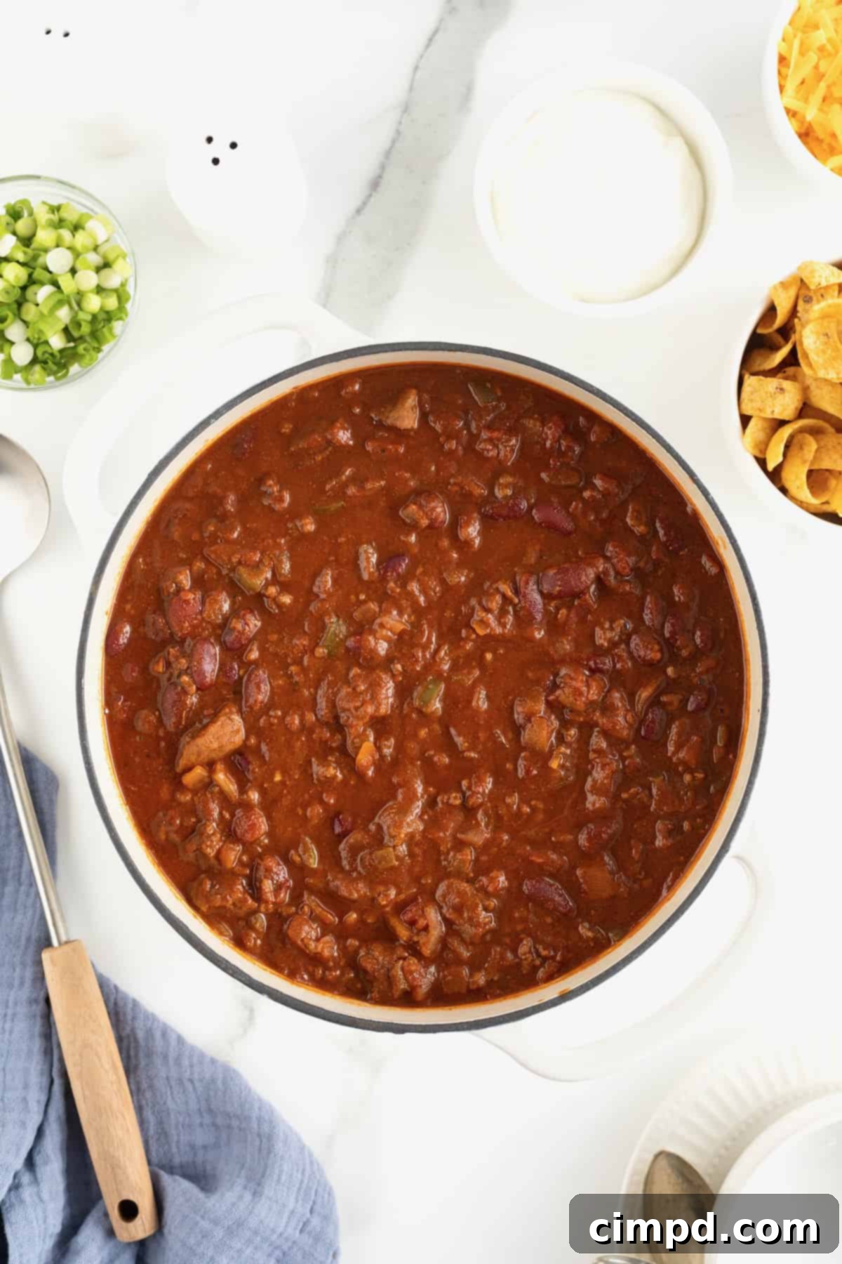 The Gold Standard Chili 9 A close-up of a steaming, dark, rich chili simmering in a Dutch oven on a light background, indicating it is perfectly cooked and ready to be served.