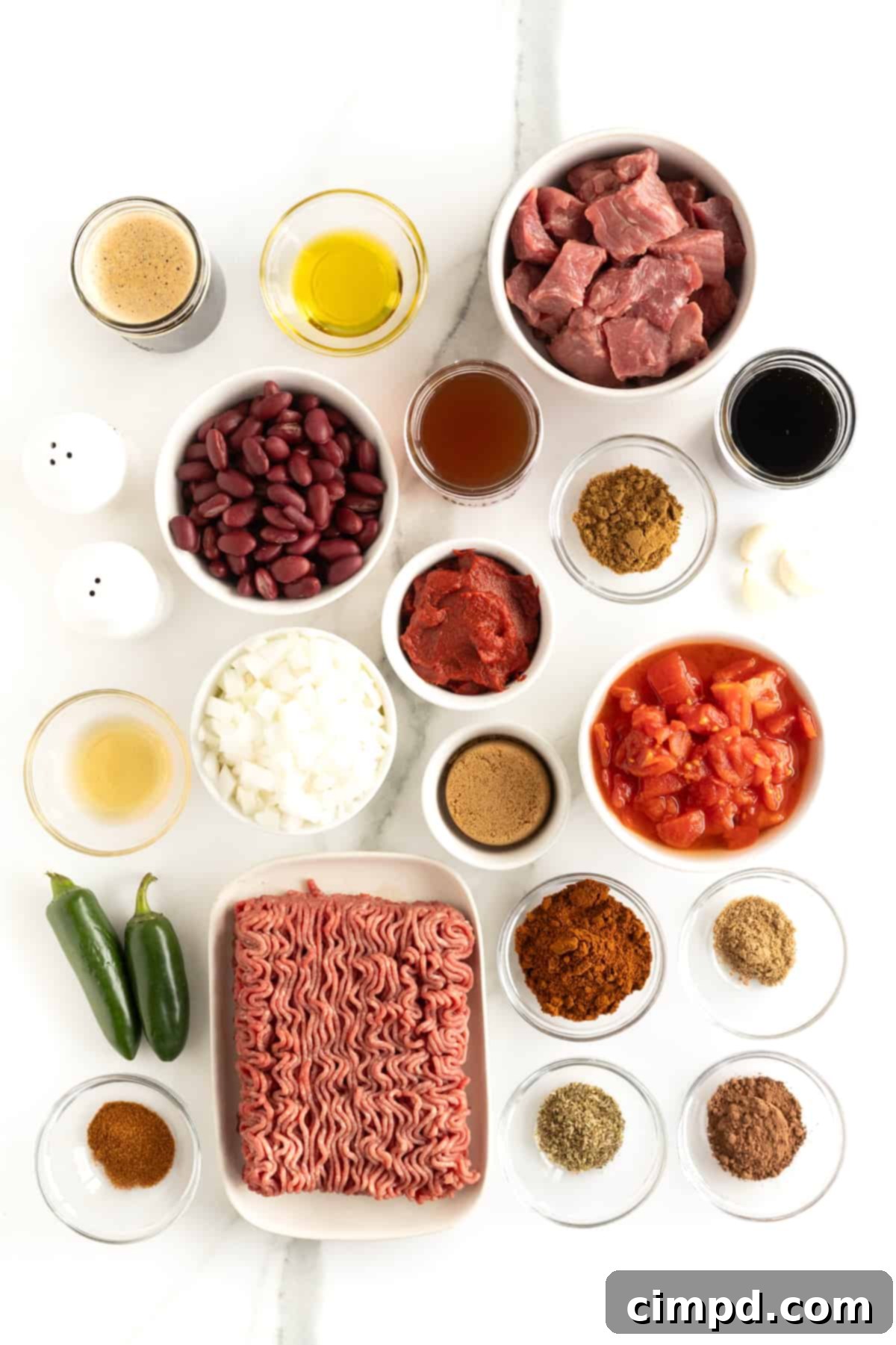 The Gold Standard Chili 6 A beautiful array of fresh ingredients for making the best chili, meticulously arranged in small glass dishes on a pristine white marble countertop, showcasing readiness for cooking.