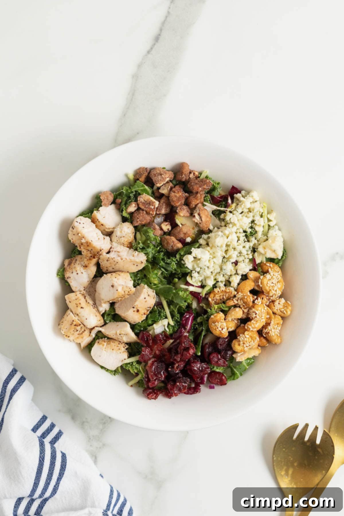 Quick 5-Minute Lunch Salad 10 Chunks of chicken, walnuts, cheese, and cranberries added to a salad in a white bowl.