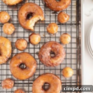 Shortcut Cinnamon Roll Donuts 12 Cinnamon roll donuts on a metal cooling rack, freshly made and glazed.