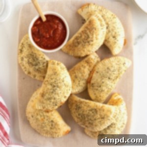 An oblong serving plate filled with mini calzones and a small white dish of marinara.