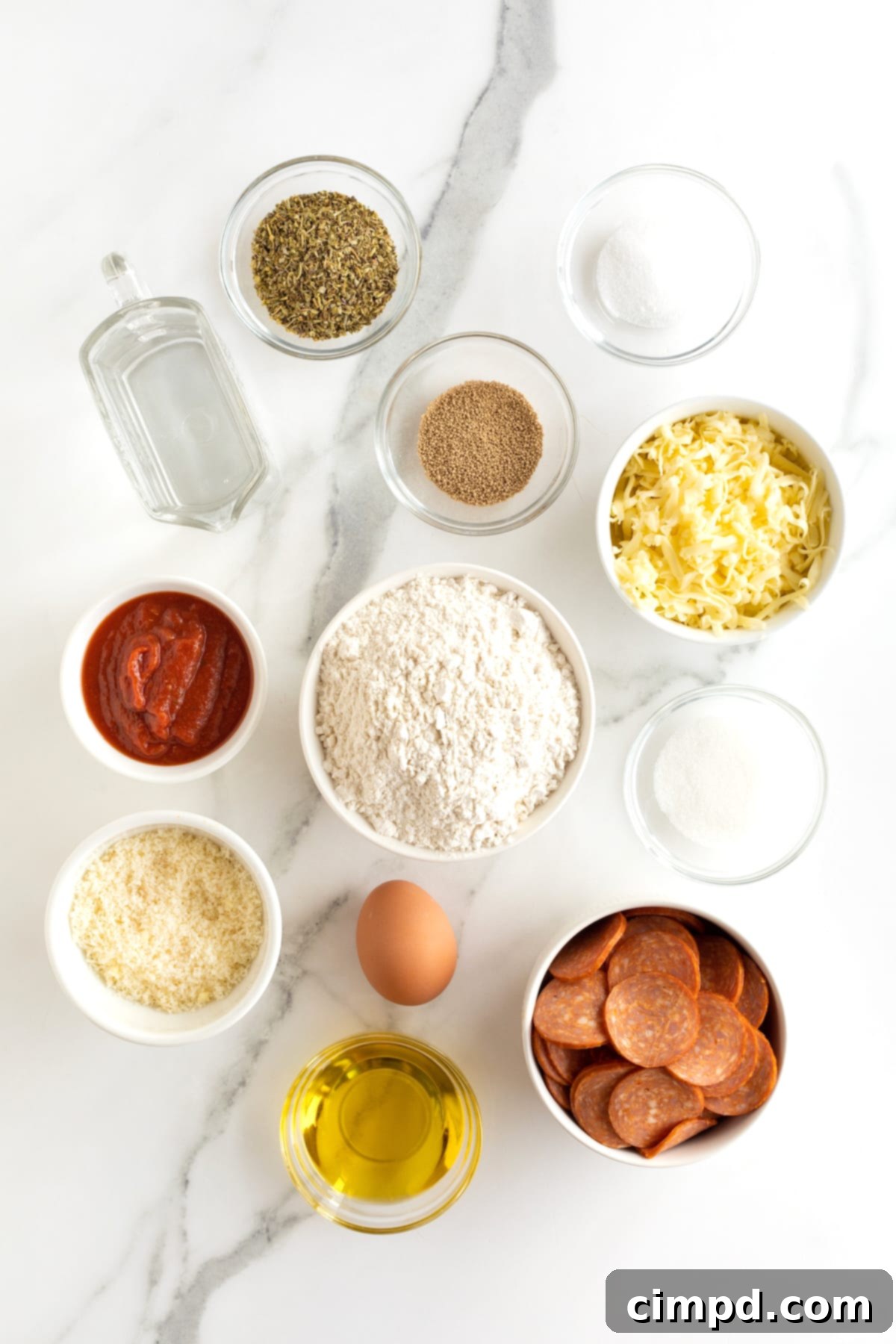 Ingredients for making mini pepperoni calzones in small white glass dishes on a white and gray marble counter.