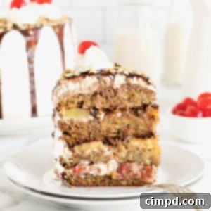 Banana Split Dream Cake 13 A slice of banana split cake on a white dessert plate. A fork rests on the bottom right of the plate.