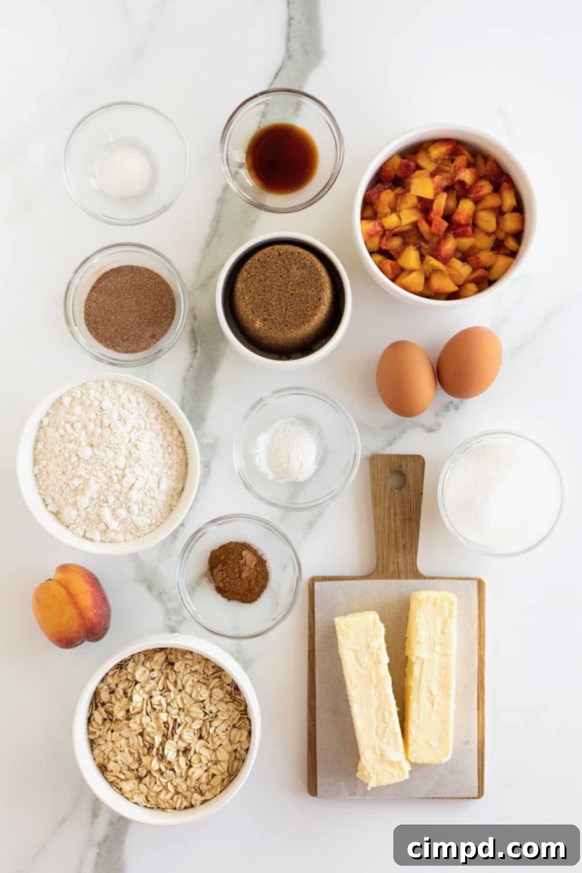 A collection of ingredients for peach oatmeal bars, including flour, oats, baking powder, salt, cinnamon, butter, sugars, eggs, vanilla, and fresh peaches, neatly arranged in small glass dishes on a white countertop.