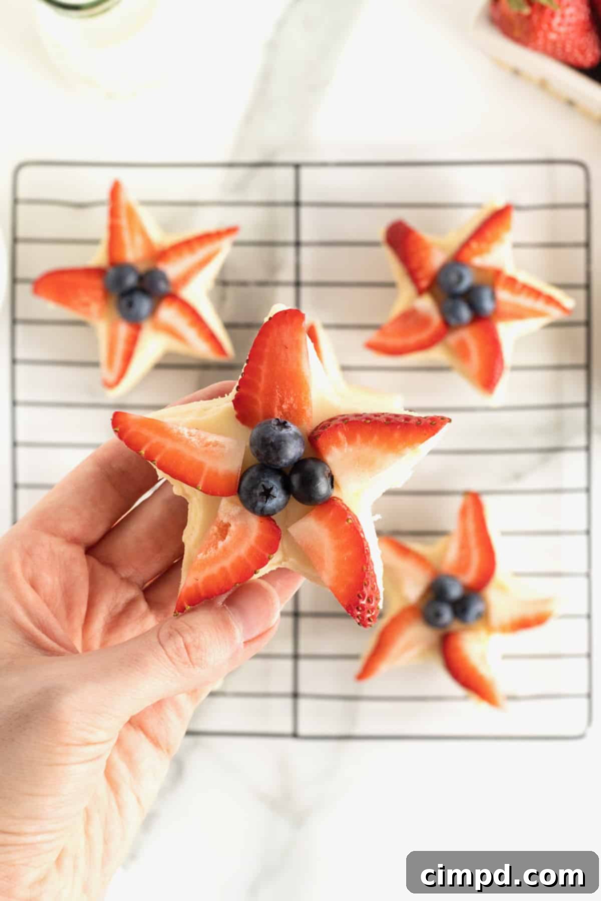 Star-Spangled Celebration Cookies 4 Close-up of star shaped shortbread cookies, artfully decorated with strawberry slices and blueberries, highlighting their festive appeal.