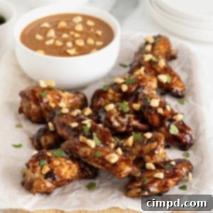 Asian chicken wings on a white surface next to a small white bowl of dipping sauce.