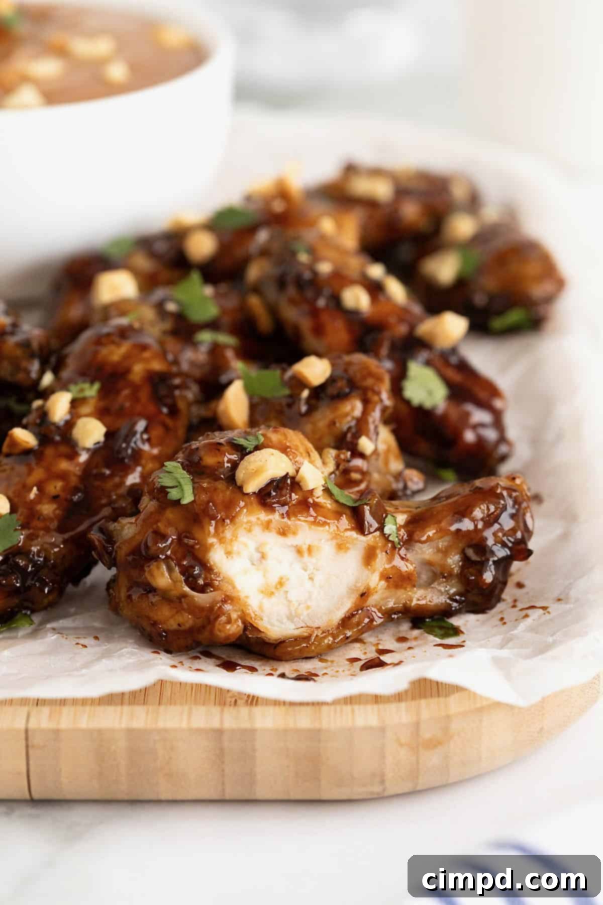 A platter of Baked Crispy Asian Chicken Wings, beautifully garnished with finely chopped fresh cilantro and crushed peanuts, ready to be served.