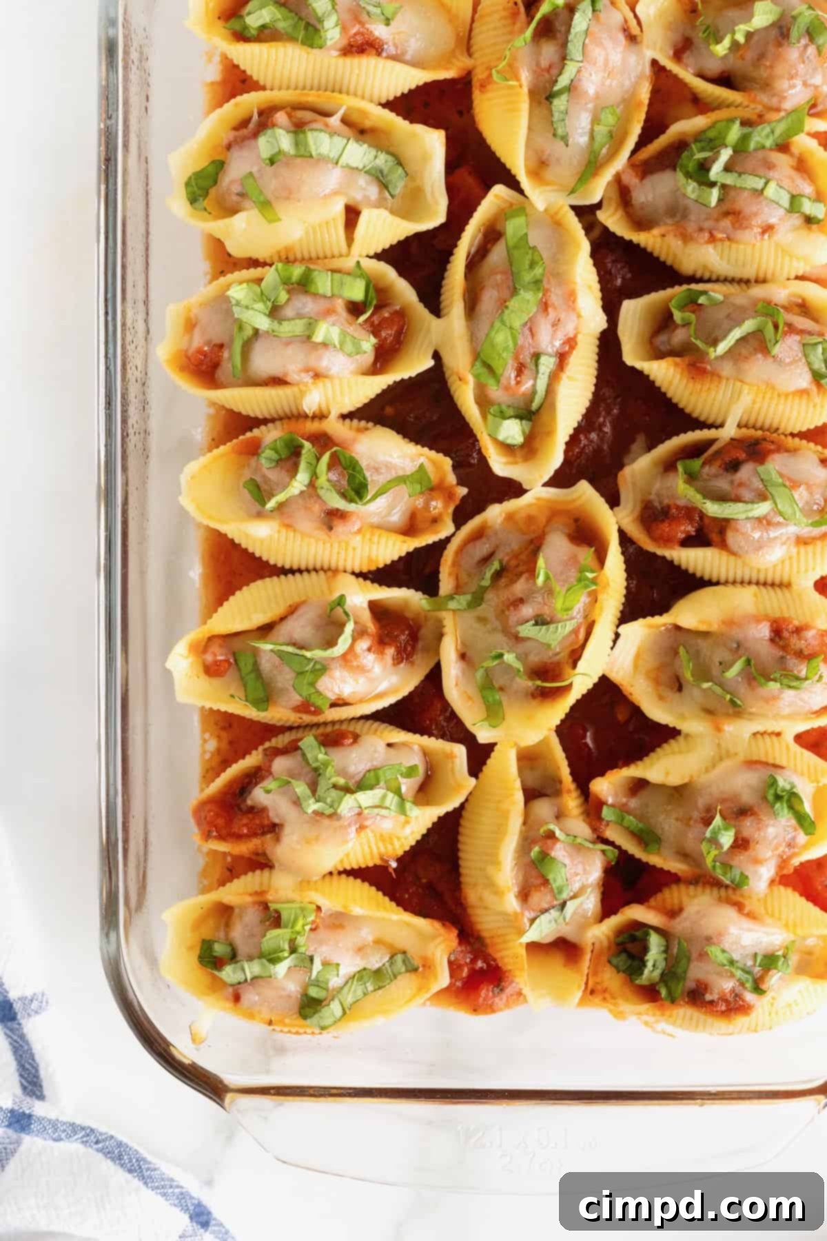 A pyrex baking dish filled with jumbo pasta shells stuffed with meatballs, sauce and mozzarella cheese.