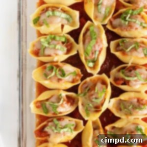 A pyrex baking dish filled with jumbo pasta shells stuffed with meatballs, sauce and mozzarella cheese.