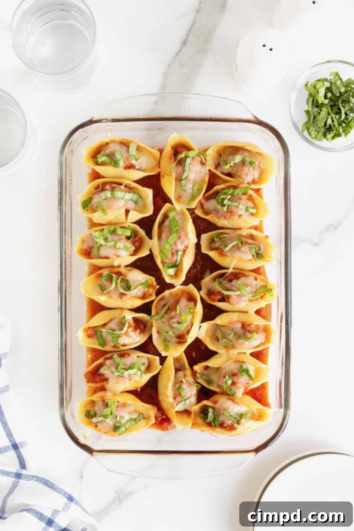 A pyrex baking dish of stuffed shells on a white marble counter.