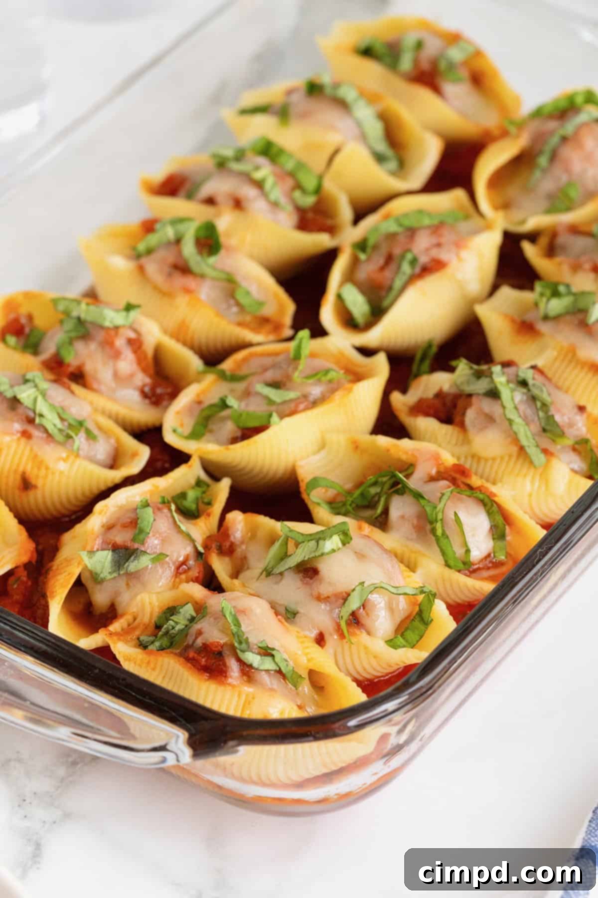 A pyrex baking dish of stuffed shells on a white marble counter.