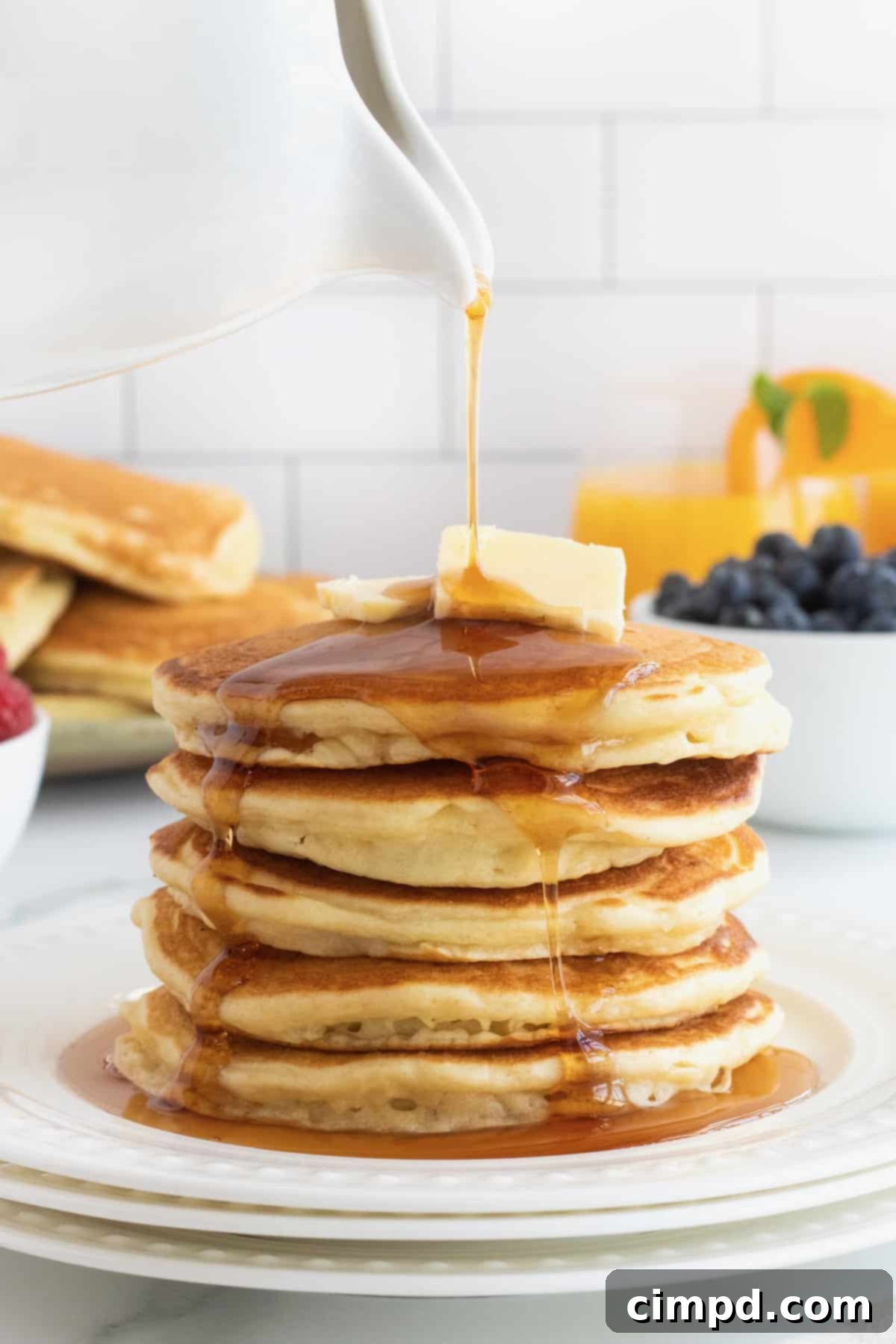 Serving of Classic Buttermilk Pancakes with a generous drizzle of maple syrup, by The BakerMama
