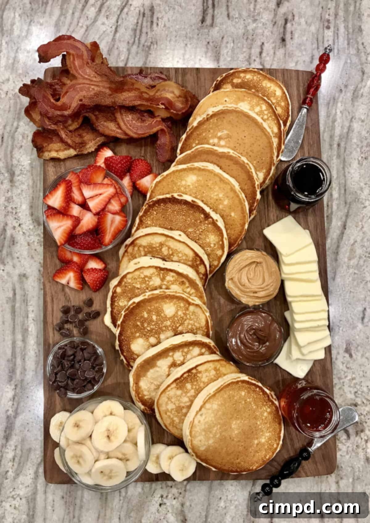A stunning Pancake Board overflowing with buttermilk pancakes, fresh fruit, bacon, and various sweet toppings, beautifully arranged for an inviting breakfast spread.